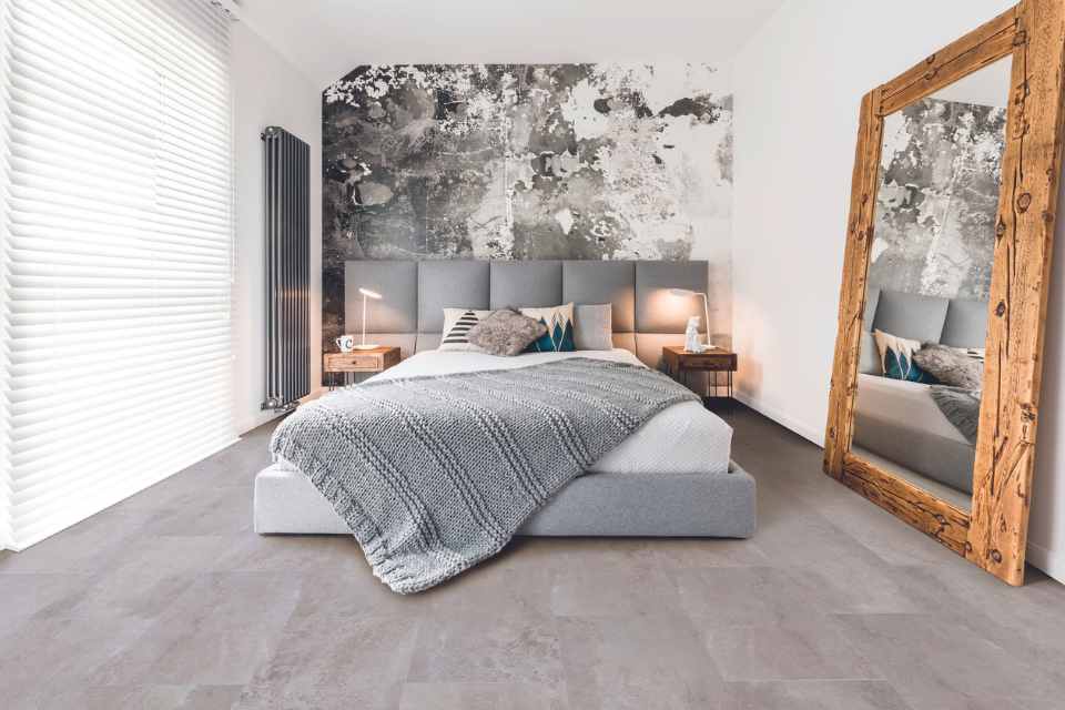 limewash bedroom with gray concrete look vinyl floor and raw wood mirror